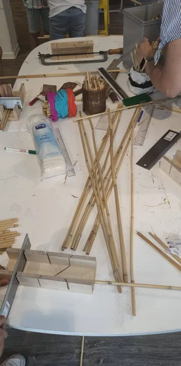 People assembling bamboo sticks on table.