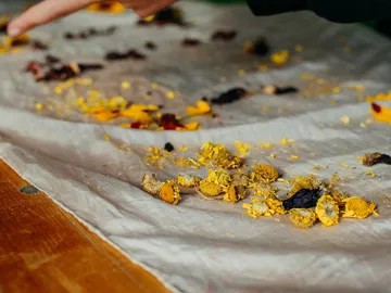 Remains of flowers are lying on a table, someone points at them.