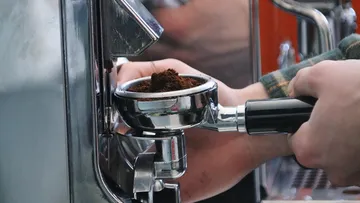Person making espresso, holding portafilter.