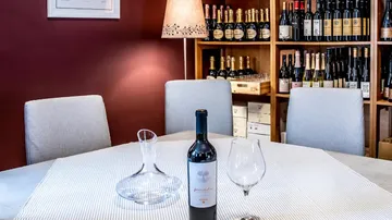 Weinflasche auf Tisch, Weinregale im Hintergrund.