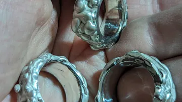 Three silver rings with textured surface, held in hand.