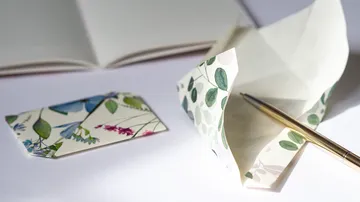Florale Umschläge und Stift auf Tisch.