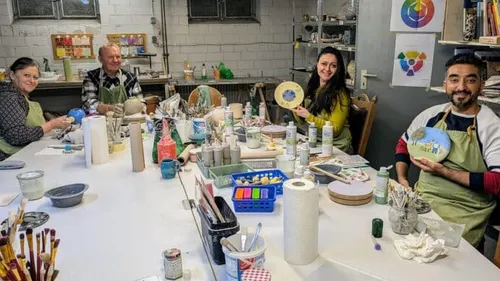 People painting ceramics at a table indoors.