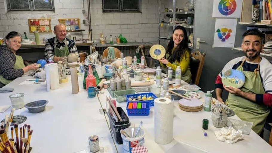 People painting ceramics at a table indoors.
