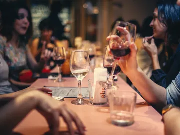 Gläser mit Wein und Wasser auf einem Tisch, geselliges Gespräch.
