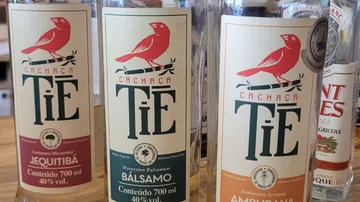 Three cachaça bottles with colorful labels displayed.
