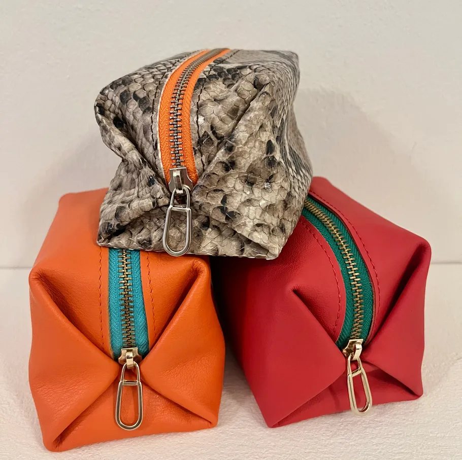 Three colorful pouches stacked on white surface.
