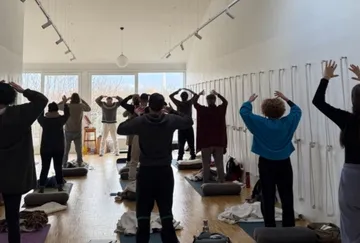 Personen praktizieren Yoga in einem hellen Raum.