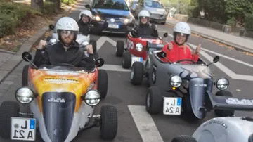 Personen fahren kleine Autos auf der Straße.