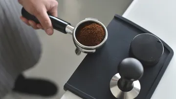 Portafilter with coffee grounds being prepared.