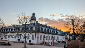 Historisches Gebäude bei Sonnenuntergang mit Bäumen.