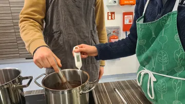 Zwei Personen bereiten Sauce in Küche vor.