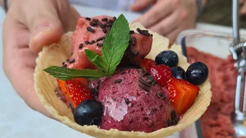 Hand holding ice cream in waffle bowl.