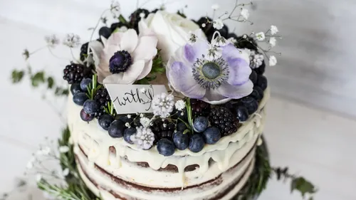 Nackter Kuchen mit Blumen und Beeren oben.