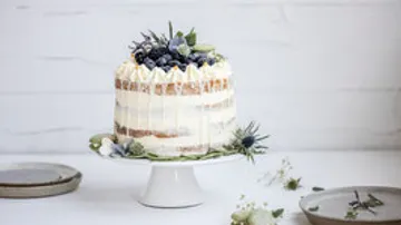 Layered cake with berries on cake stand.