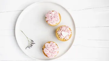 Drei Cupcakes mit rosa Zuckerguss auf Teller.