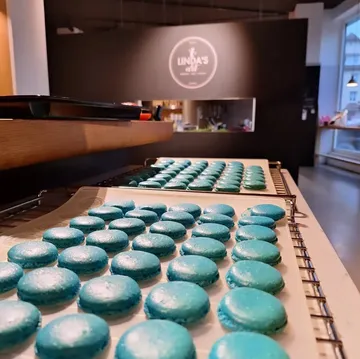 Blaue Macarons auf Tabletts in einer Küche.