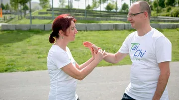 Two people practicing Tai Chi outdoors.