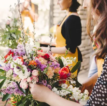 Frauen arrangieren bunte Blumen draußen.