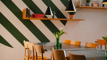 Esstisch mit Stühlen und dekorativer Wand.