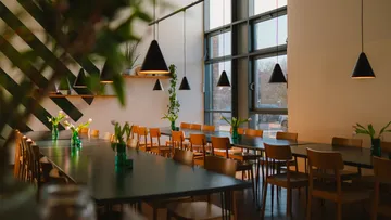 Leeres Café mit Holzstühlen, grünen Pflanzen.