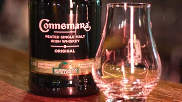 Whiskeyflasche und Glas auf Holztisch.