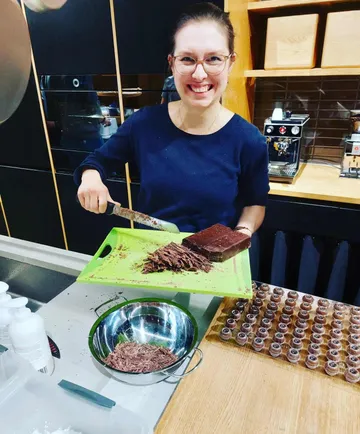 Person chopping chocolate in kitchen setting.