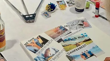 Craft table with collage materials, papers, items.