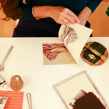 Person revealing print on white paper, artistic workspace.