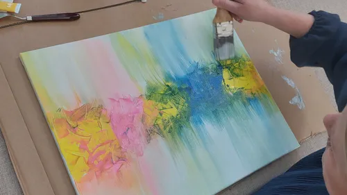 Person painting an abstract colorful canvas.