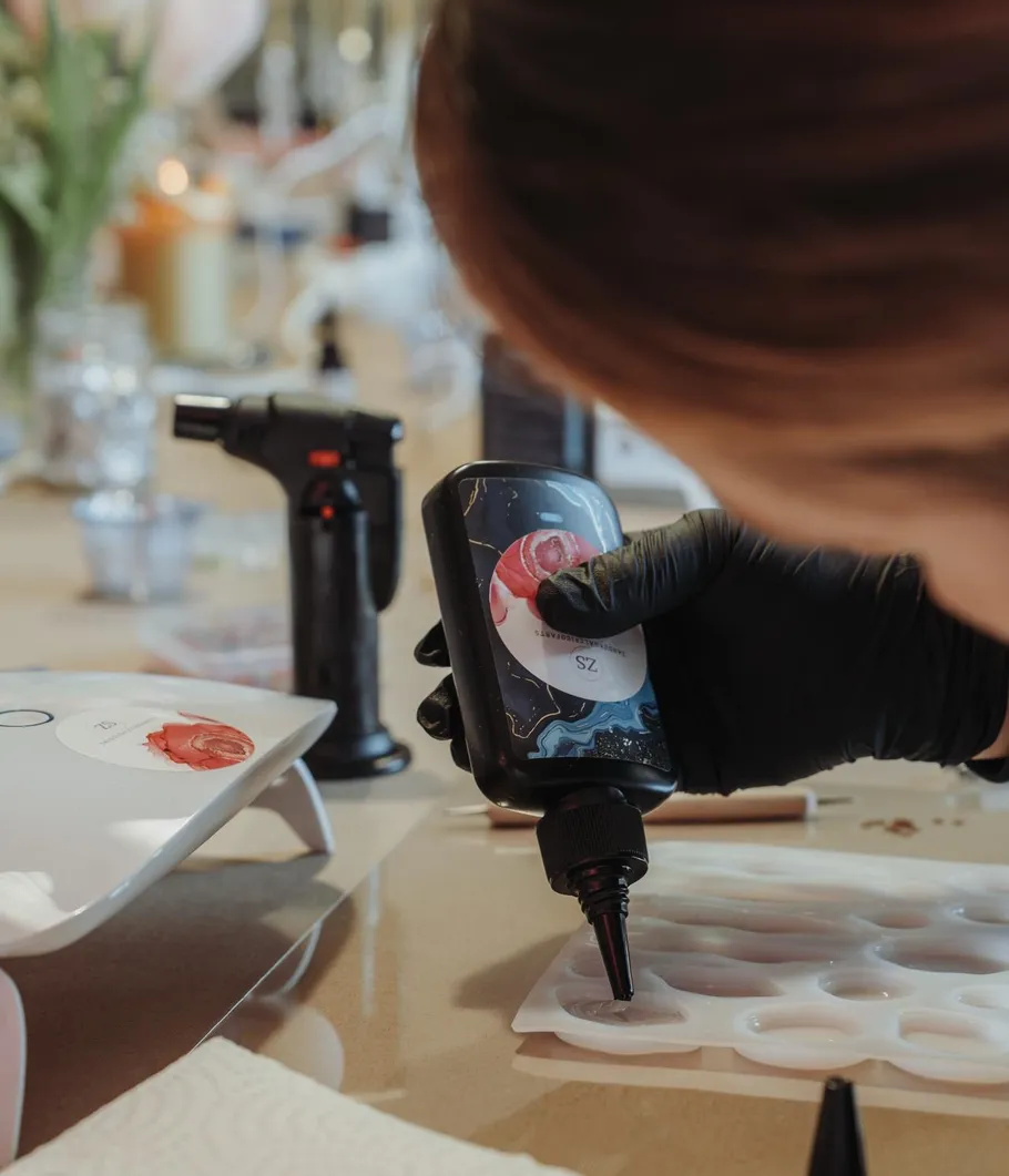 Person pouring liquid into mold on table.