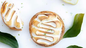 Zitronen-Baiser-Törtchen mit Blättern daneben.