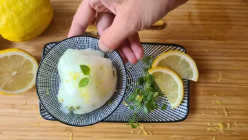 Hand placing sorbet with lemon slices on board.