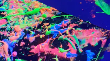 Neonfarbe auf dunkler Oberfläche gespritzt.