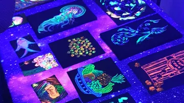 Colorful UV paintings arranged on glowing table.
