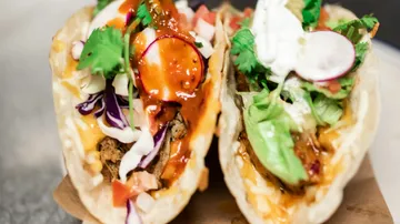 Two tacos filled with vegetables and sauce.