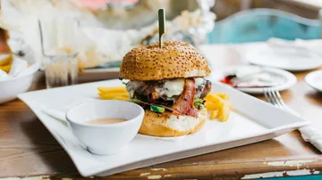 Burger mit Pommes und Soße auf einem Teller.