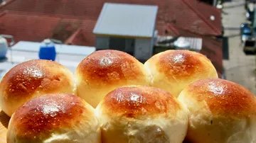 Goldene Brötchen im Sonnenlicht, städtischer Hintergrund.