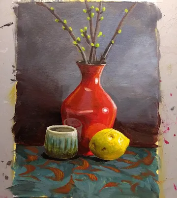 Red vase with branches, cup, lemon on table.