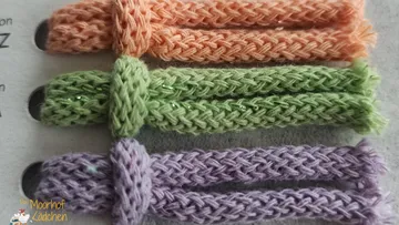 Three knitted worms on a surface.