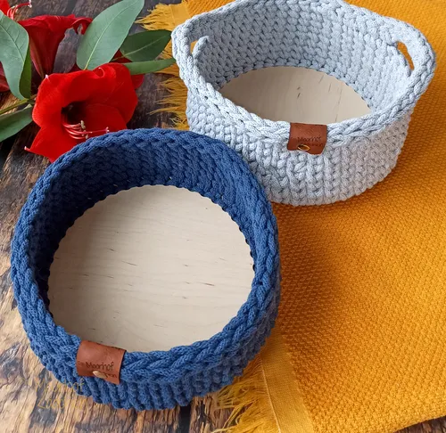 Häkelkörbe auf Tisch, Blumen in der Nähe.