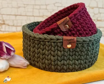 Two knitted baskets on a yellow cloth.