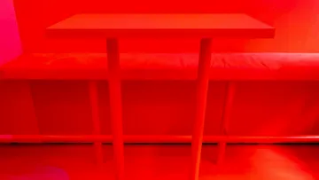 Roter Tisch und Bank in rotem Raum.