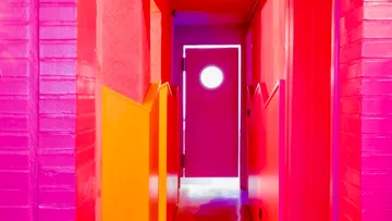 Heller pinker Flur mit runder Fenstertür.