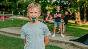 Child with blue tongue in park, smiling friends.