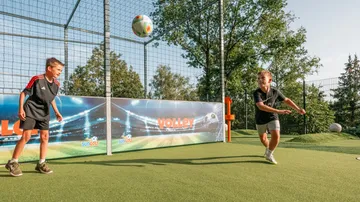 Zwei Jungen spielen Fußball auf Kunstrasen.