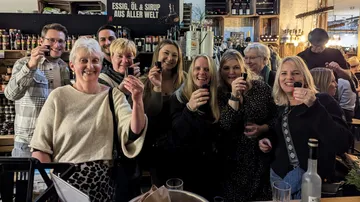 Gruppe von Menschen mit kleinen Gläsern drinnen.