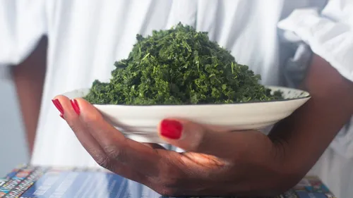 Person holding a plate of leafy greens.