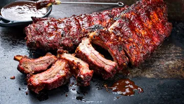 Juicy ribs with barbecue sauce on platter.