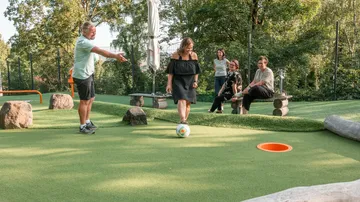 People playing football golf in a park.